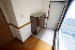 AIで荷物を消しています。ライトコートから入る光で、訪れる人に住空間の大きさを印象付けます。シューズボックスの上にお花や写真を飾っても良いですね。
